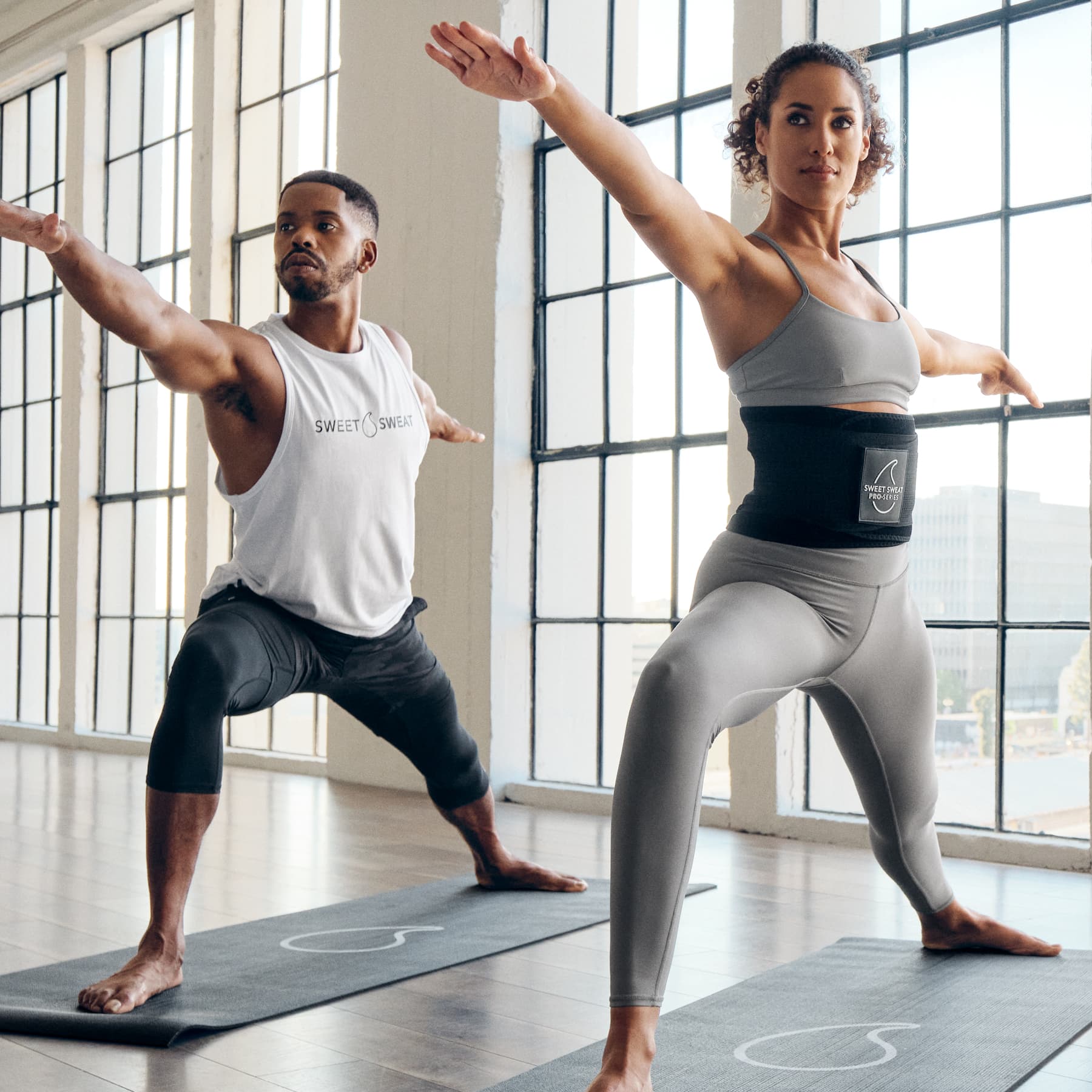 a man and a woman doing yoga in a large room.